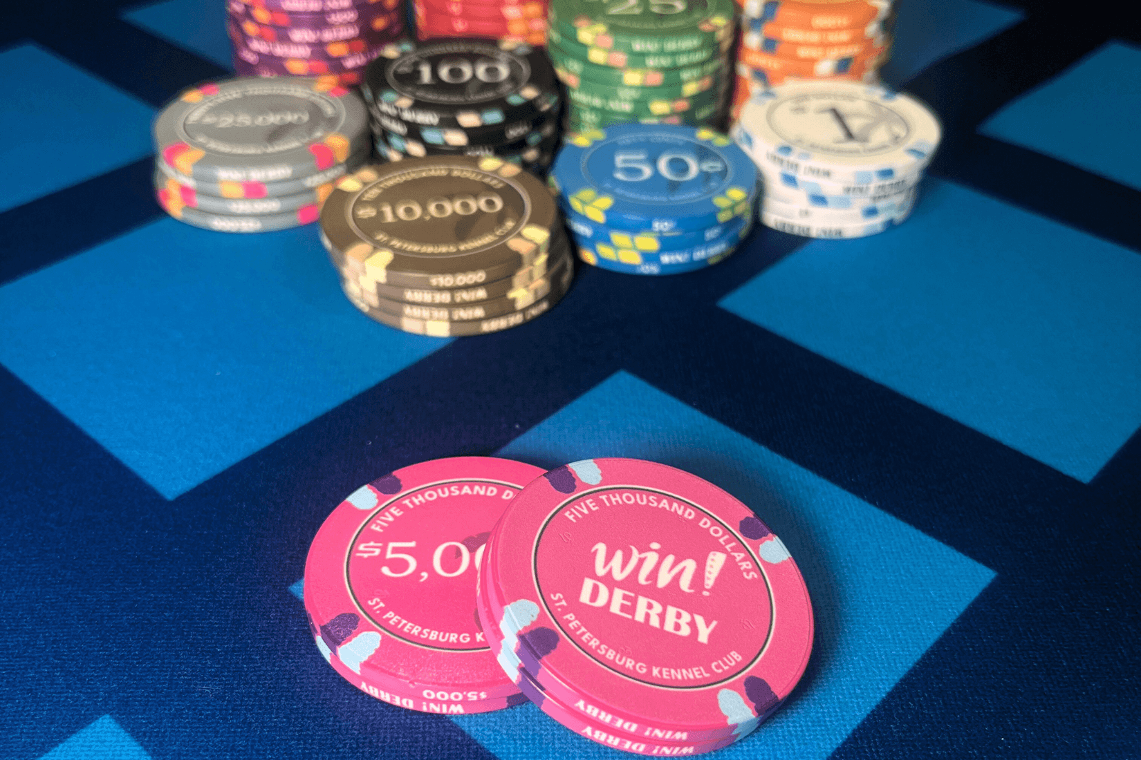 Poker chip values and colors showing standard casino chip denominations and a pink win derby chip for $5,000